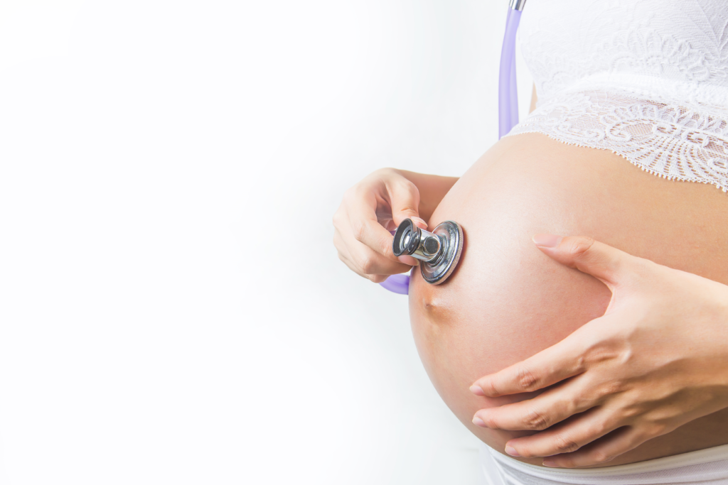  A pregnant lady with a stethoscope trying to hear the heartbeat of the fetus