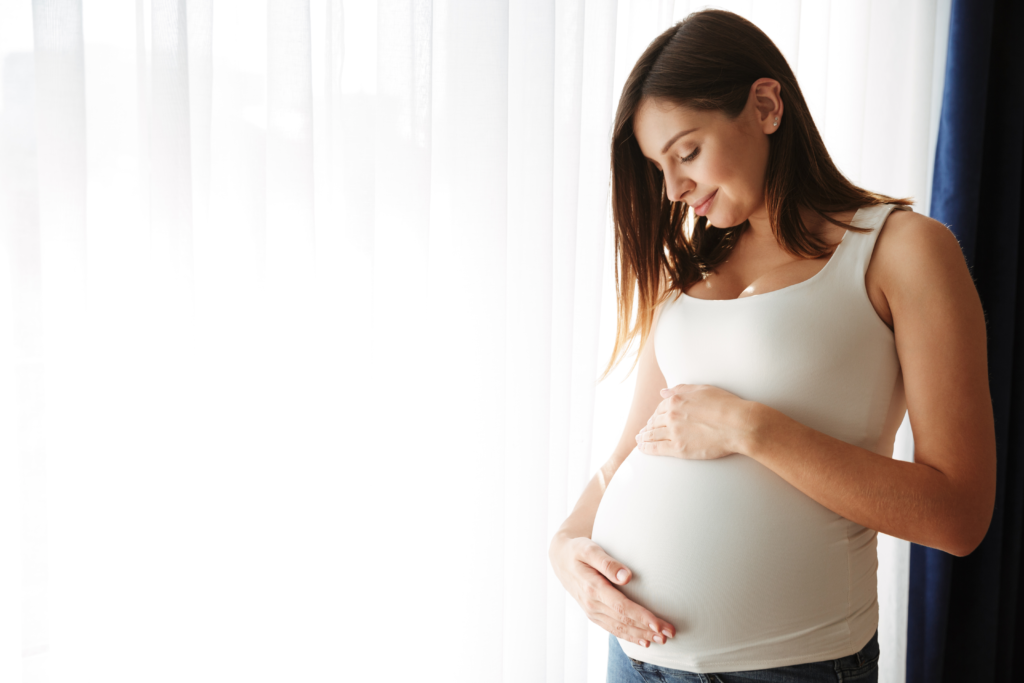 A happy pregnant lady touching her womb.